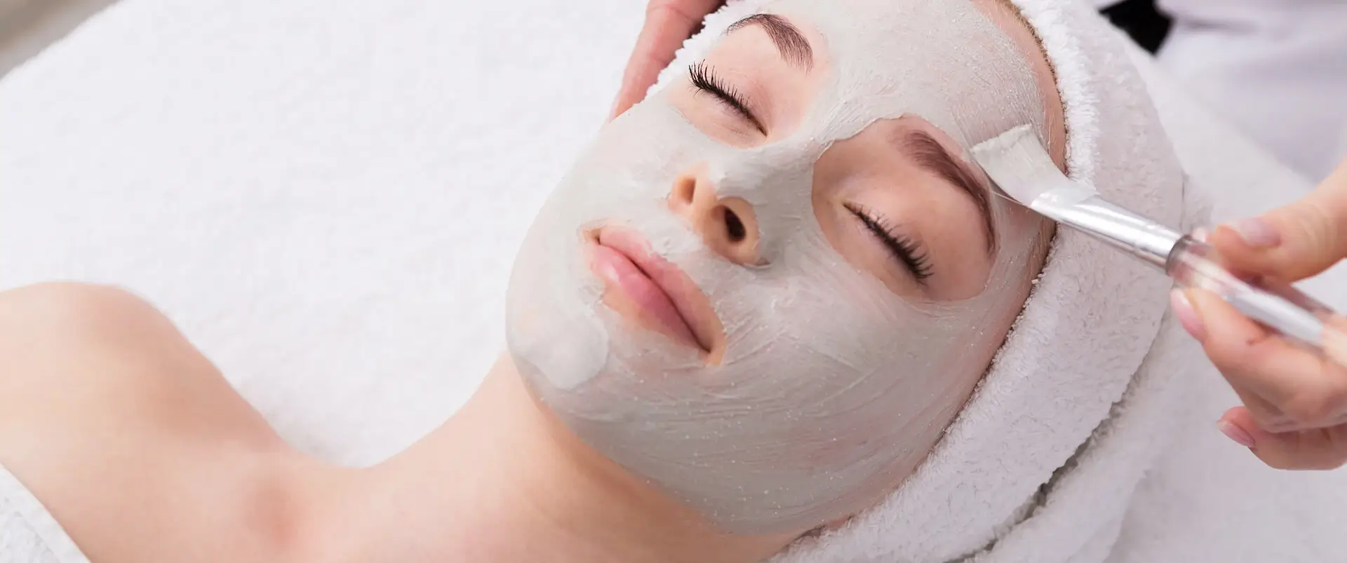 Une femme se fait faire un masque de beauté par une esthéticienne au salon de beauté Purlux.