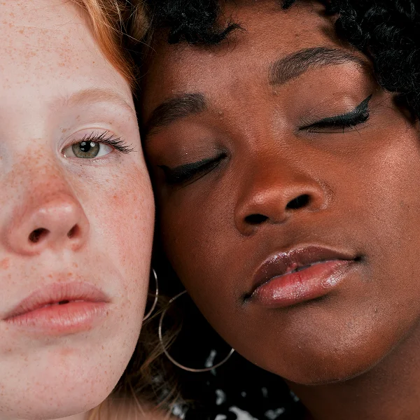 Deux femmes aux yeux fermés regardent l'objectif, exprimant une connexion calme et sereine.