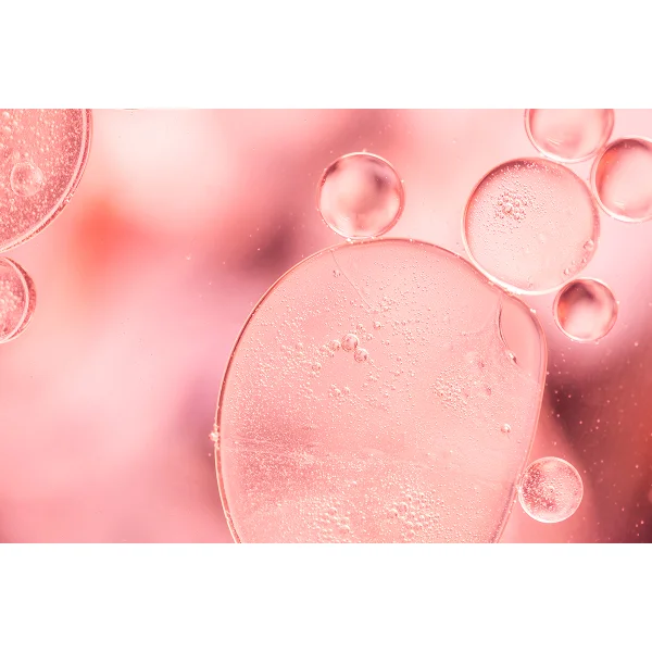 Des bulles d'eau flottent dans un liquide rose, évoquant des éléments de collagène et d'élastine.