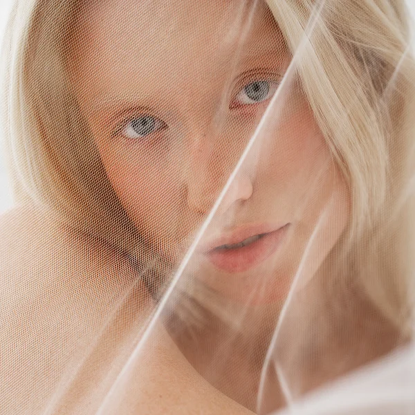 Une femme avec un drap blanc couvrant son visage, effet Ultra Glow accentuant la luminosité de son teint.