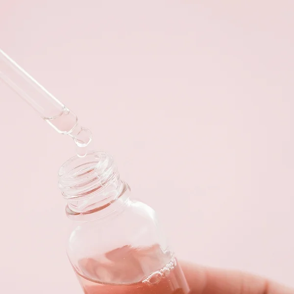 Une personne tenant une petite bouteille de liquide pour un traitement laser non ablatif.