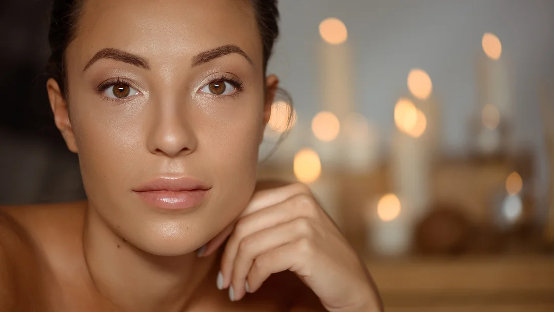 Femme au visage magnifique, avec une bougie en arrière-plan, effet Ultra Glow accentuant la lumière douce.